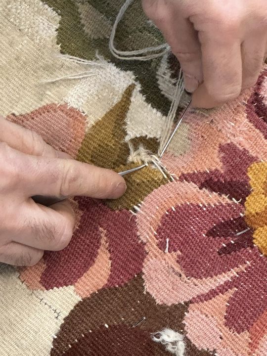 Aiguille et laine passées dans une tapisserie d'Aubusson à décor floral