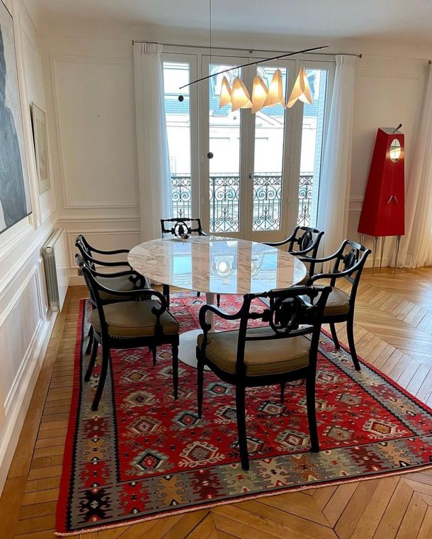 Kilim rouge à motifs géométriques sous une table en marbre, dans une salle à manger parisienne
