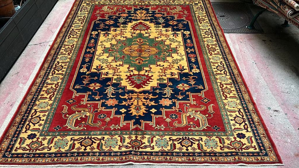 Tapis Kazak noué main à médaillon central vert et or sur fond bleu nuit, champ et bordure rouges